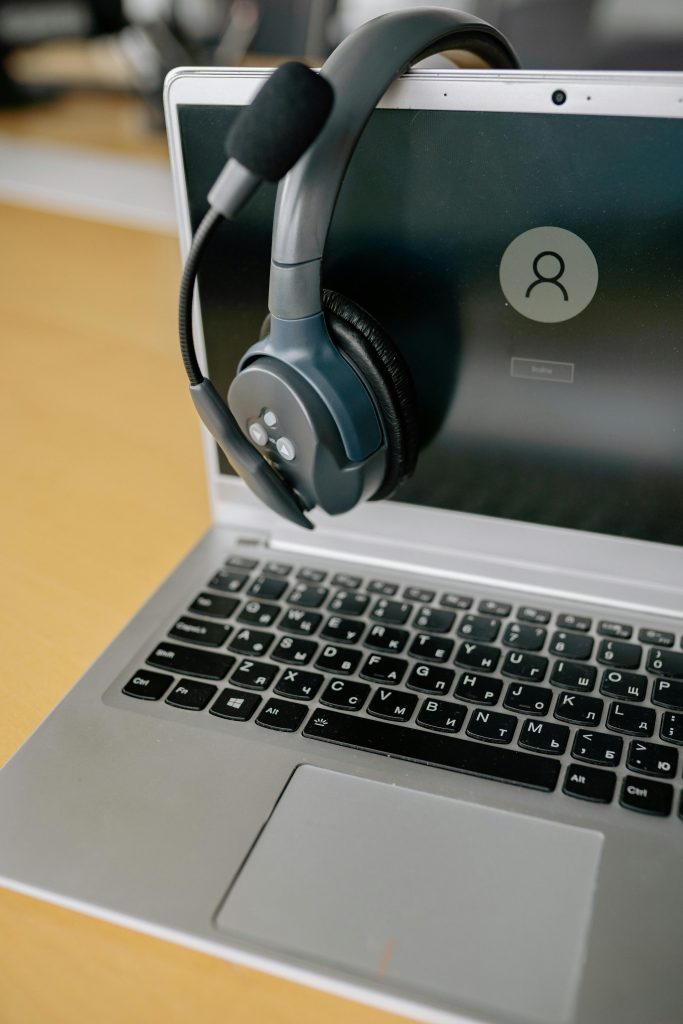 pexels-photo-8866735-8866735 Close-up of a laptop with a headset, symbolizing online communication and remote work.